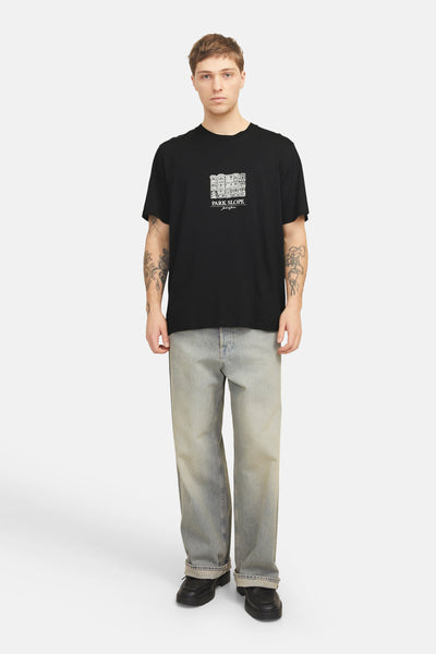 Zwart T-shirt met korte mouwen van ORIGINALS BY JACK & JONES met witte grafische print, gedragen met een verbleekte spijkerbroek.