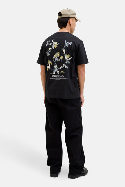 T-shirt à manches courtes noir de ORIGINALS BY JACK & JONES, avec motif floral imprimé au dos et porté avec pantalon noir et casquette beige.