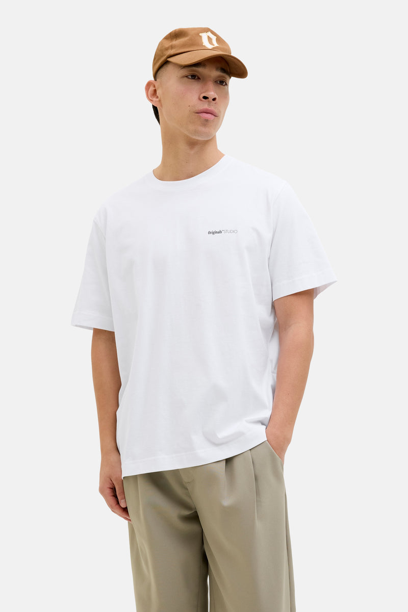 Wit T-shirt met korte mouwen van ORIGINALS BY JACK & JONES, gedragen met een wijde beige broek en een bruine pet.