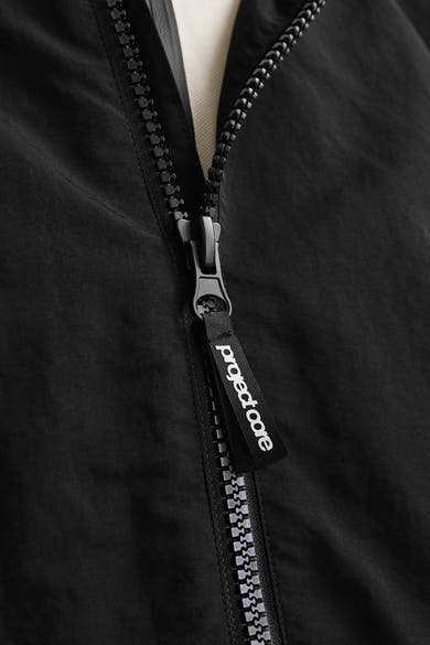 Korte zwarte jas van JACK & JONES met ritssluiting en een trekker met logo.