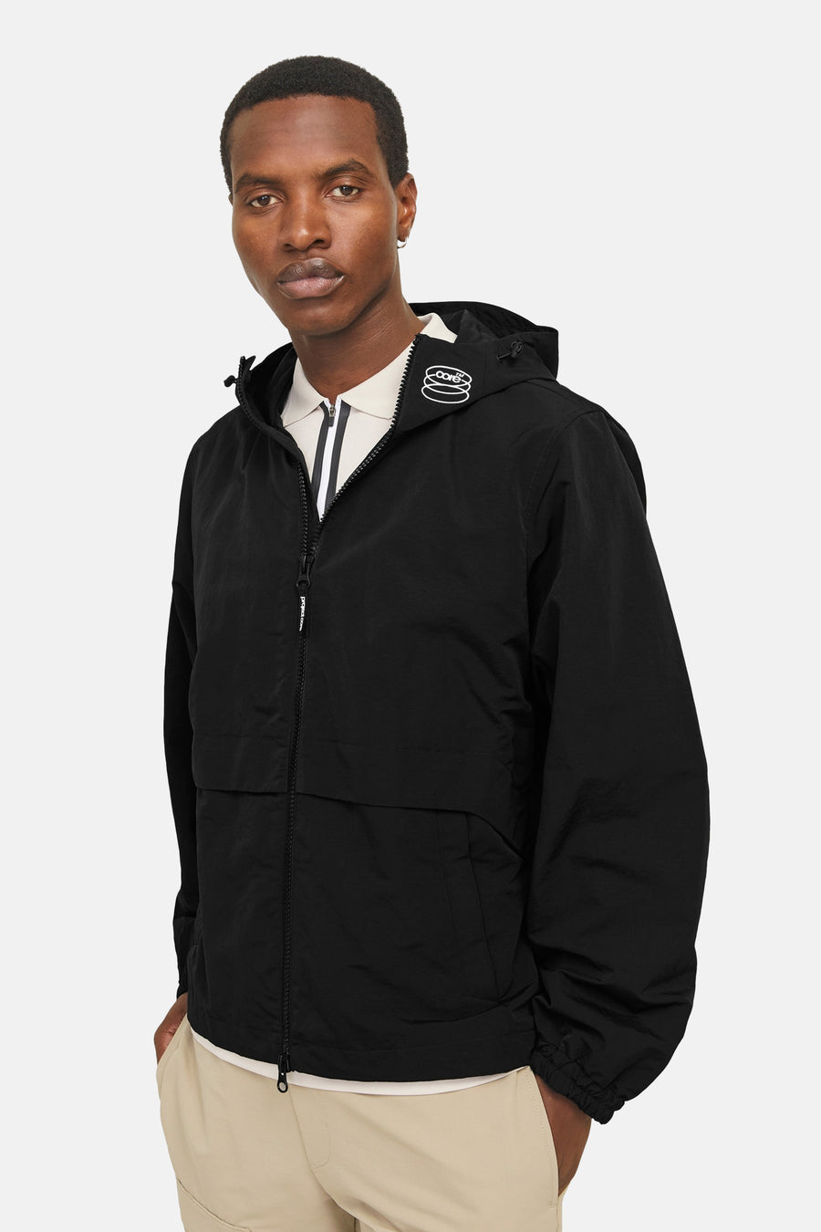 Korte zwarte jas van JACK & JONES met capuchon, ritssluiting en wit logo.