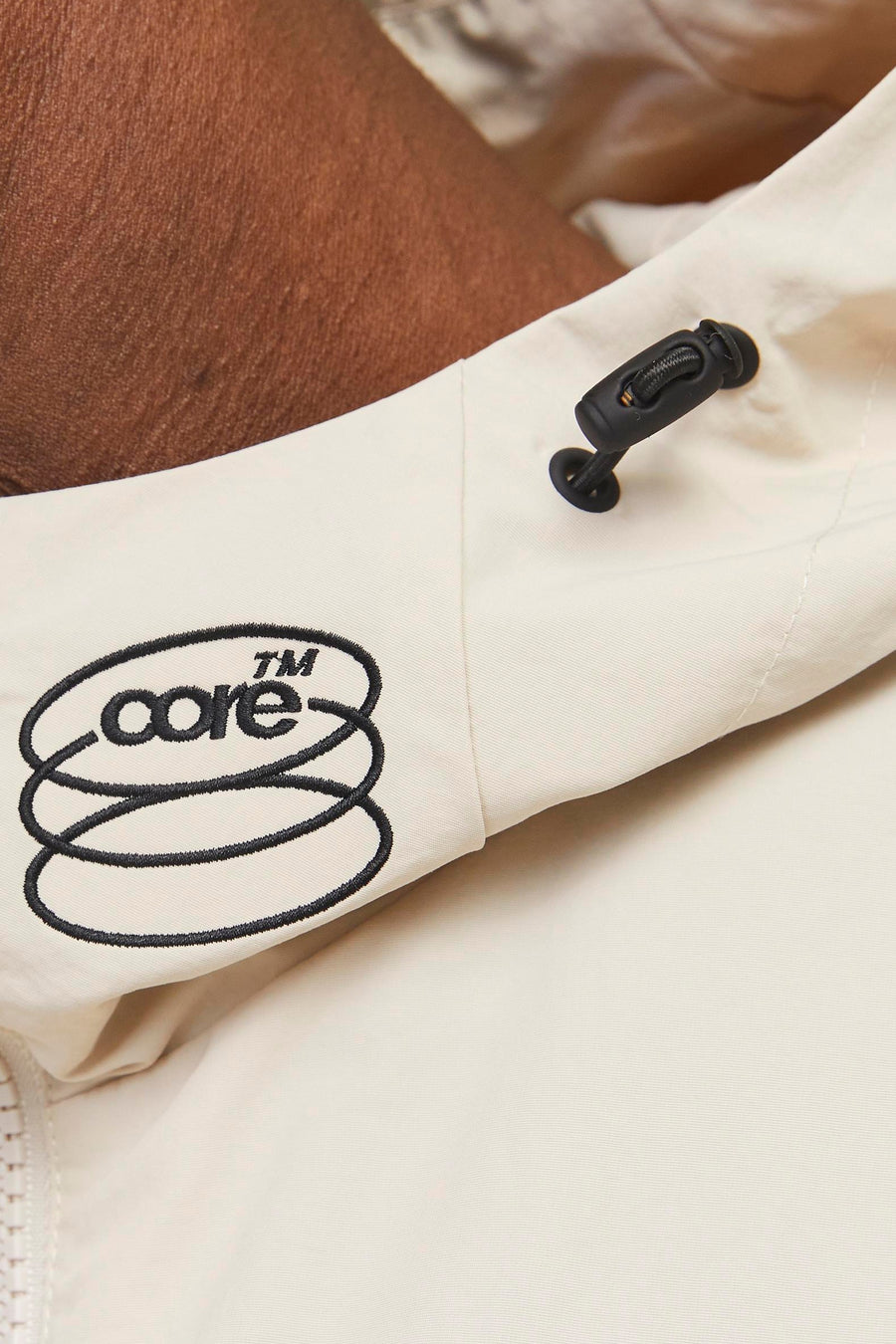 Korte beige jas van JACK & JONES, met zwart trekkoord en geborduurd logo.