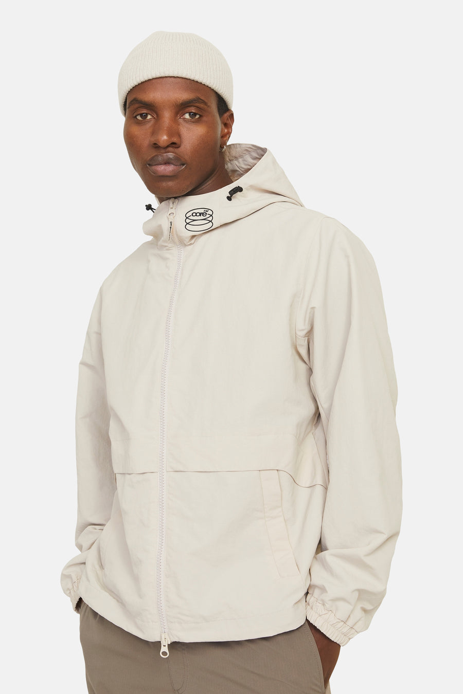 Korte beige jas van JACK & JONES, met capuchon en ritssluiting op een witte achtergrond.