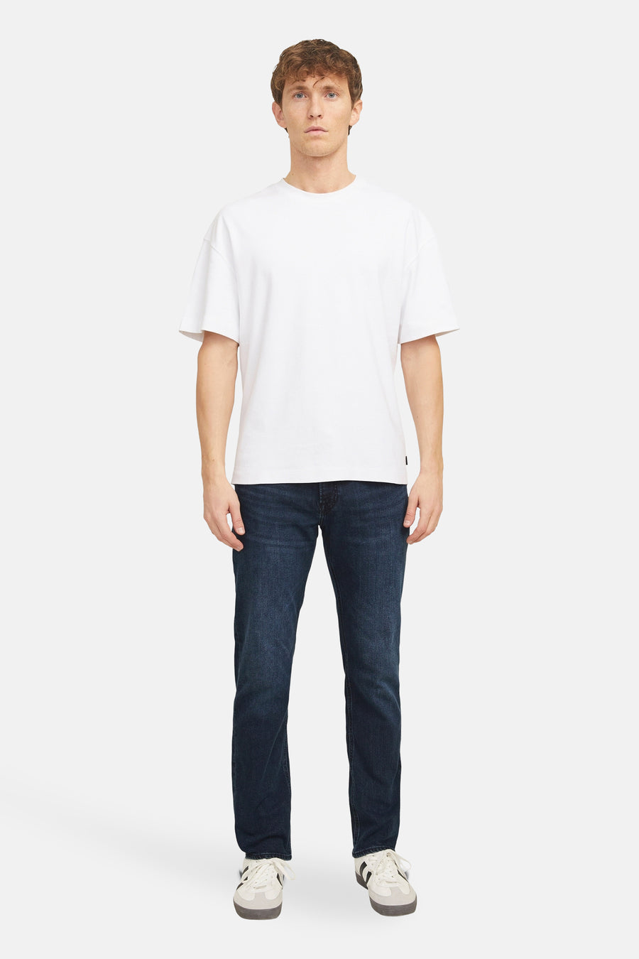 Jean droit en denim bleu foncé de JACK & JONES JEANS INTELLIGENCE, porté avec un t-shirt blanc et des baskets.