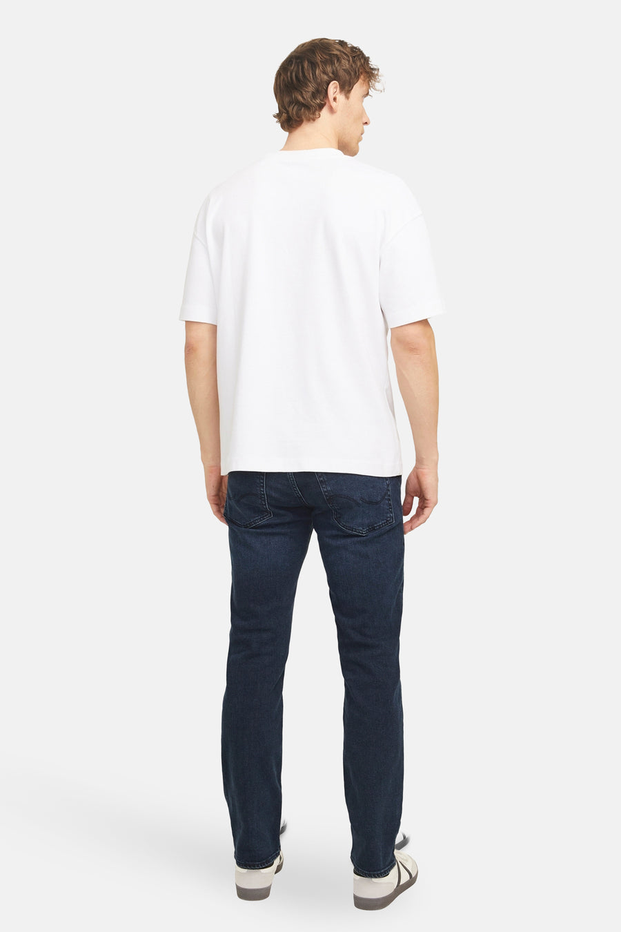 Rechte donkerblauwe jeans van JACK & JONES JEANS INTELLIGENCE, gedragen met een wit T-shirt en neutrale sneakers, achtergezicht.