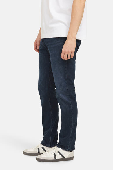 Rechte donkerblauwe jeans van JACK & JONES JEANS INTELLIGENCE, gedragen met witte sportschoenen.