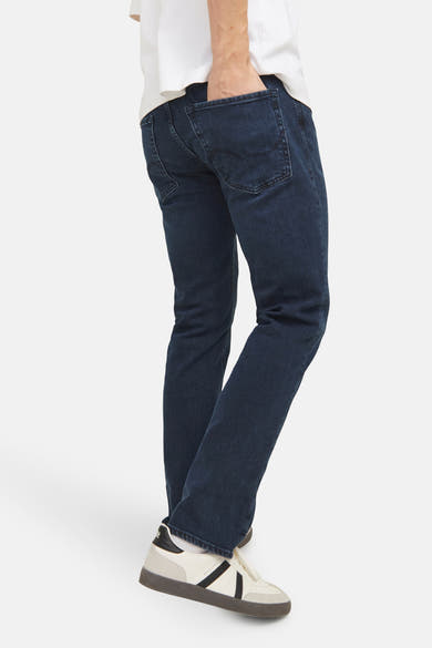 Rechte donkerblauwe jeans van JACK & JONES JEANS INTELLIGENCE, gedragen met een wit T-shirt en retro sneakers.