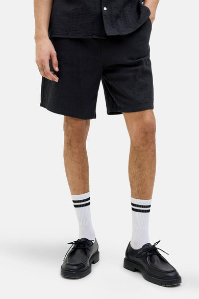 Korte broek van ORIGINALS BY JACK & JONES, relaxte pasvorm, gedragen met witte sokken met strepen en zwarte schoenen.