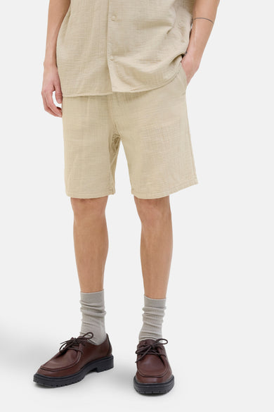 Korte beige short van ORIGINALS BY JACK & JONES, gedragen met een bijpassend overhemd, grijze sokken en bruine schoenen.