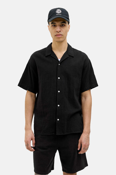 Chemise noire à manches courtes par ORIGINALS BY JACK & JONES, portée avec une casquette noire assortie et un t-shirt blanc aperçu.