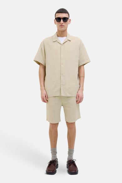 Beige overhemd met korte mouwen van ORIGINALS BY JACK & JONES, gedragen met een wit T-shirt en een bijpassende korte broek.