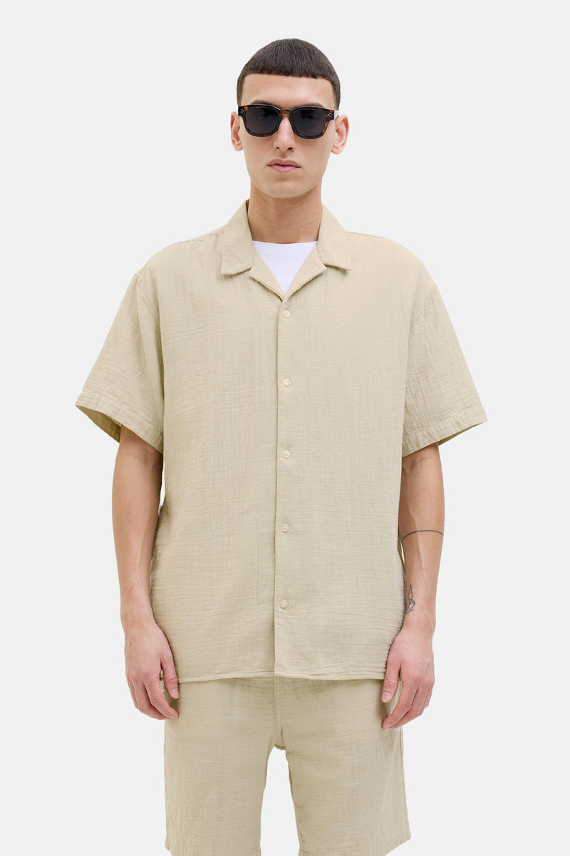Beige overhemd met korte mouwen van ORIGINALS BY JACK & JONES in getextureerde stof, gedragen met een wit T-shirt en een zonnebril.