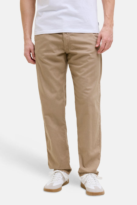 Pantalon coloré beige de JACK & JONES, avec des détails de couture visibles et des chaussures blanches.