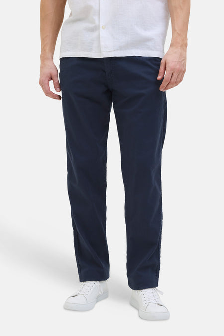 Pantalon coloré bleu de JACK & JONES, porté avec une chemise blanche et des chaussures de sport blanches.