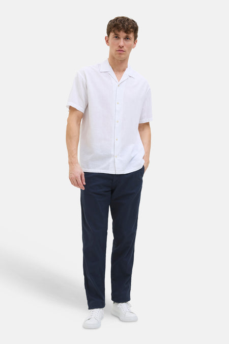 Pantalon coloré bleu de JACK & JONES, porté avec une chemise blanche et des baskets blanches.