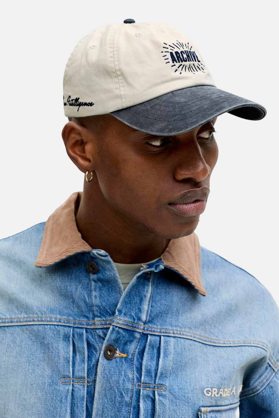 Beige pet met een marineblauwe klep en borduursel aan de voorkant, van Accessories by Jack & Jones, gedragen met een blauwe spijkerjas.