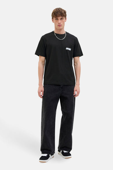 Zwarte t-shirt met korte mouwen van JACK & JONES, gedragen met een breed zwarte jeans en sneakers.