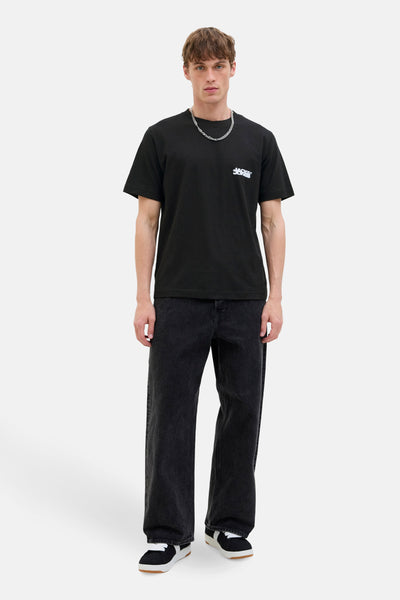 Zwarte t-shirt met korte mouwen van JACK & JONES, gedragen met een breed zwarte jeans en sneakers.