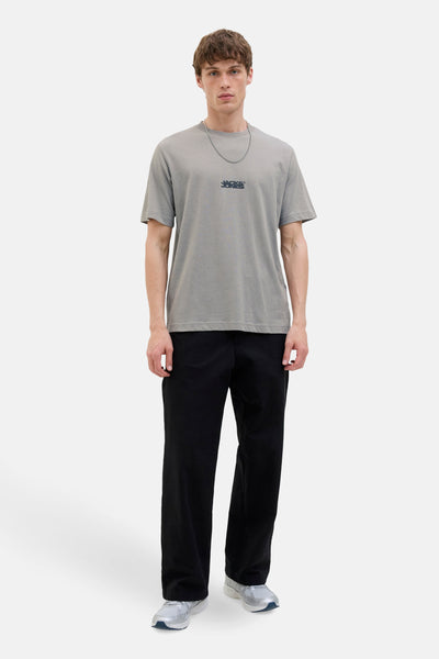 T-shirt gris à manches courtes de JACK & JONES, porté avec un pantalon noir ample et des chaussures de sport.