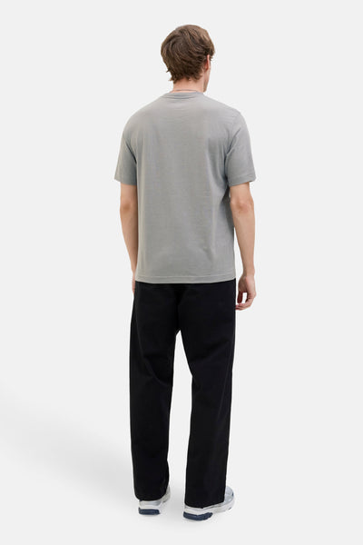 T-shirt à manches courtes gris de JACK & JONES, porté avec un pantalon noir ample et des baskets.