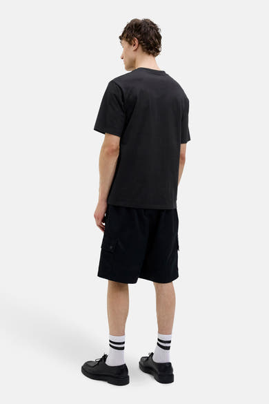 T-shirt à manches courtes noir de ORIGINALS BY JACK & JONES, porté avec un short cargo noir, des chaussettes blanches rayées et des chaussures noires.
