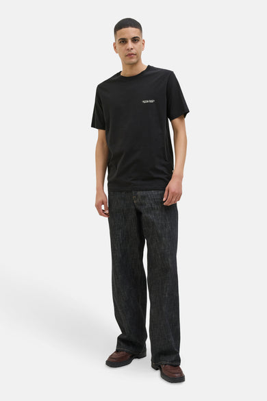 T-shirt à manches courtes noir de JACK & JONES, porté avec un jean ample et des mocassins marron.
