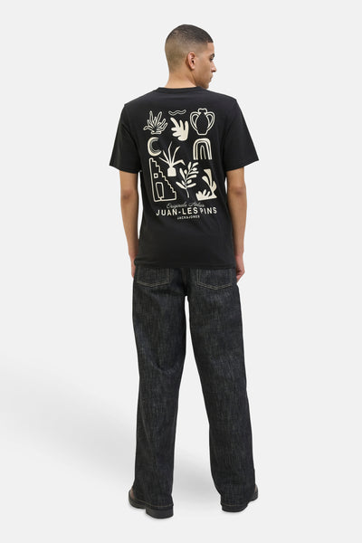 T-shirt à manches courtes noir de JACK & JONES, avec un imprimé décoratif au dos, porté avec un jean ample foncé.
