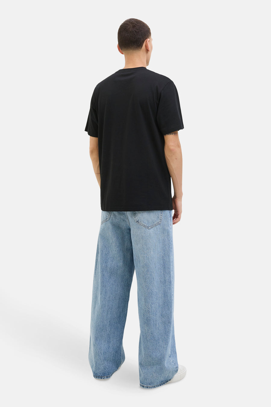 T-shirt à manches courtes noir de Originals by Jack & Jones, porté avec un jean large et des baskets blanches.