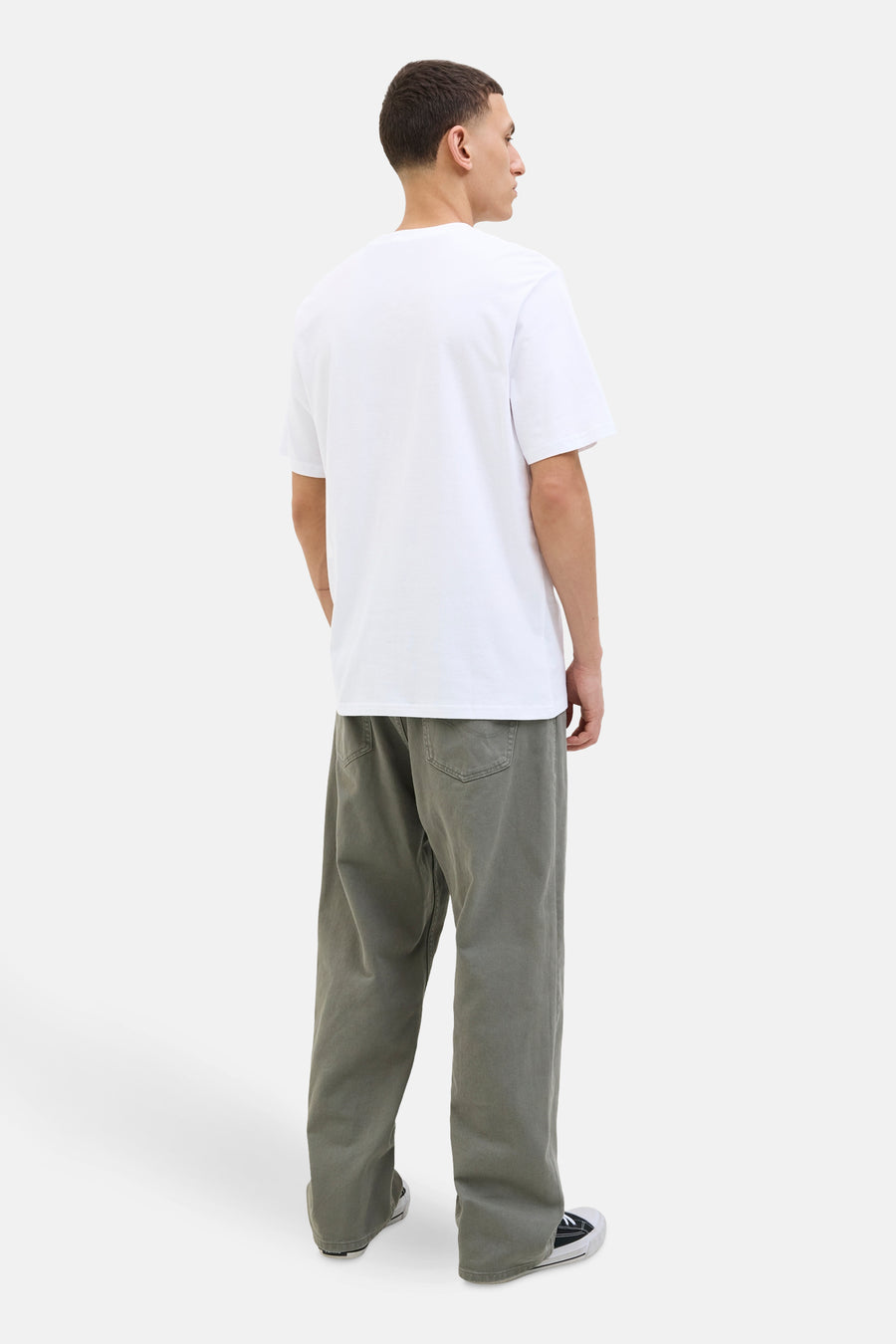 T-shirt blanc à manches courtes de ORIGINALS BY JACK & JONES, porté avec un pantalon ample kaki et des baskets noires et blanches.