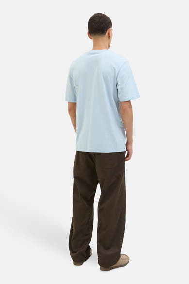 T-shirt bleu à manches courtes de ORIGINALS BY JACK & JONES, porté avec un pantalon marron et des mocassins.