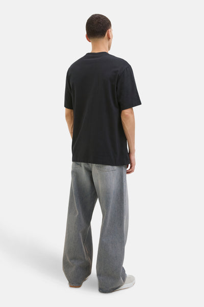 T-shirt noir à manches courtes de JACK & JONES, porté avec un pantalon large en denim délavé.