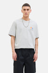 Grijs T-shirt met korte mouwen van JACK & JONES, met een grafische print op de voorkant, gedragen met een zilveren ketting.
