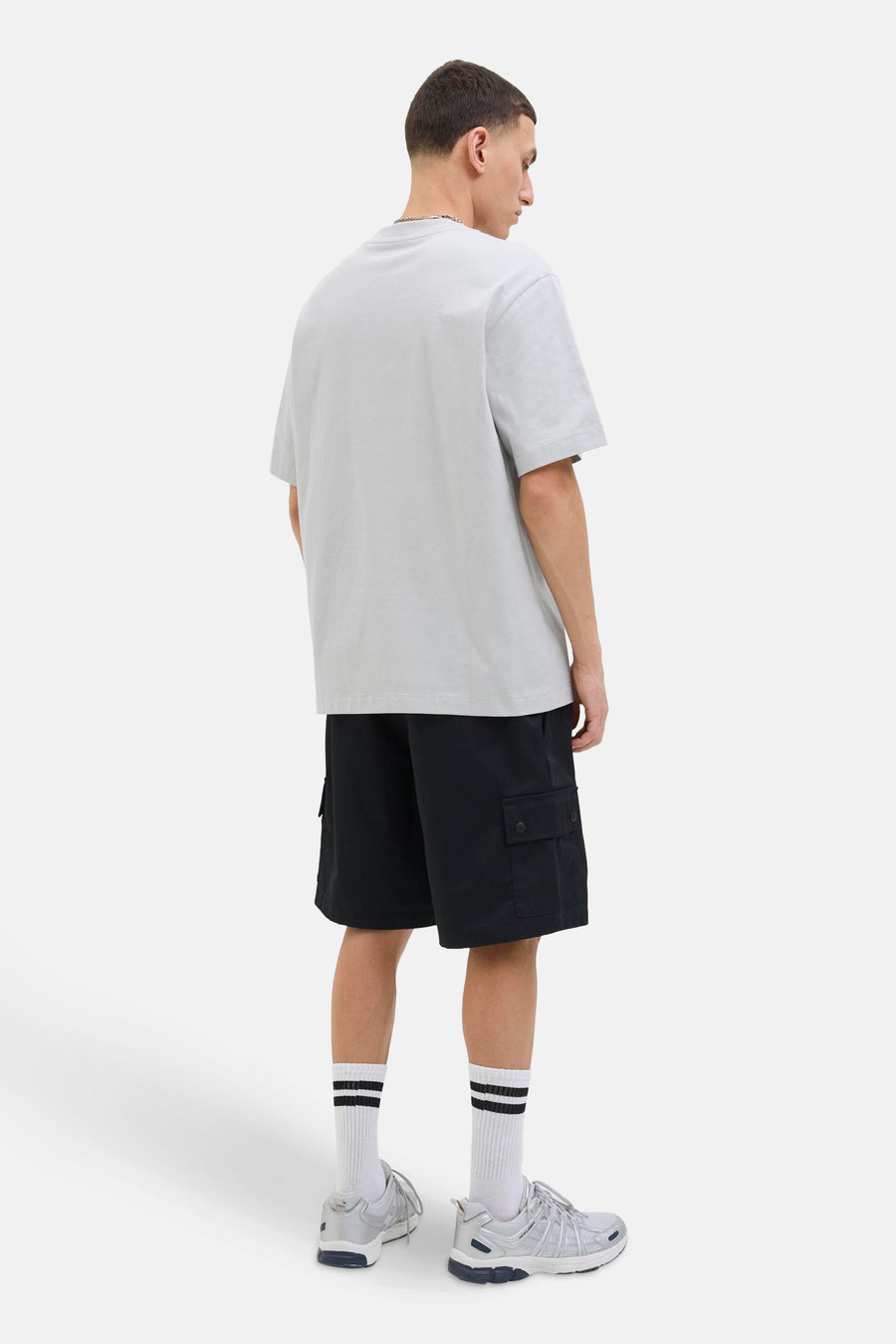 Grijs T-shirt met korte mouwen van JACK & JONES, gedragen met een zwarte cargoshort en zilveren sneakers.