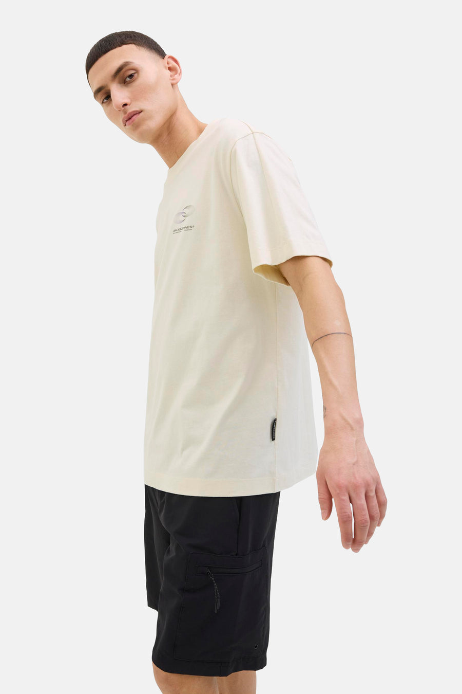 Beige T-shirt met korte mouwen van JACK & JONES, met een subtiele print op de voorkant, gedragen met een zwarte korte broek.