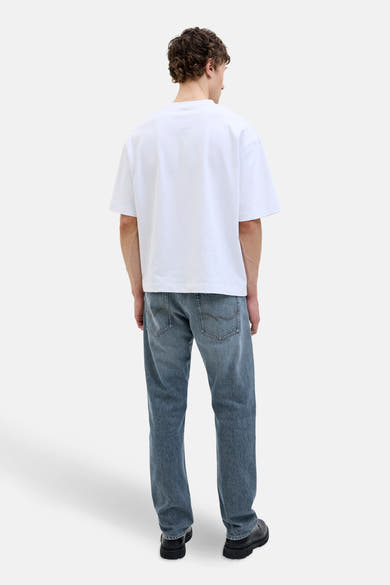 Jean fuselé bleu moyen en denim de JACK & JONES JEANS INTELLIGENCE, porté avec un t-shirt blanc et des chaussures noires, vue de dos.
