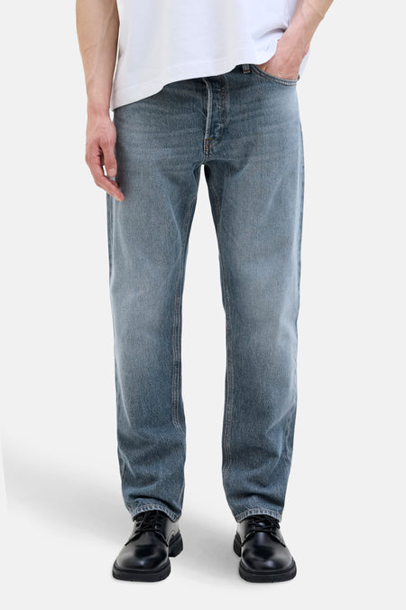 Taps toelopende jeans in middinblauw denim van JACK & JONES JEANS INTELLIGENCE, gedragen met een wit T-shirt en zwarte schoenen.