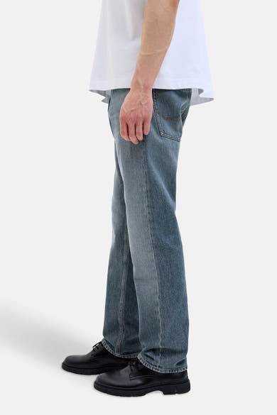Jean fuselé en denim bleu moyen de JACK & JONES JEANS INTELLIGENCE avec des chaussures noires à lacets.
