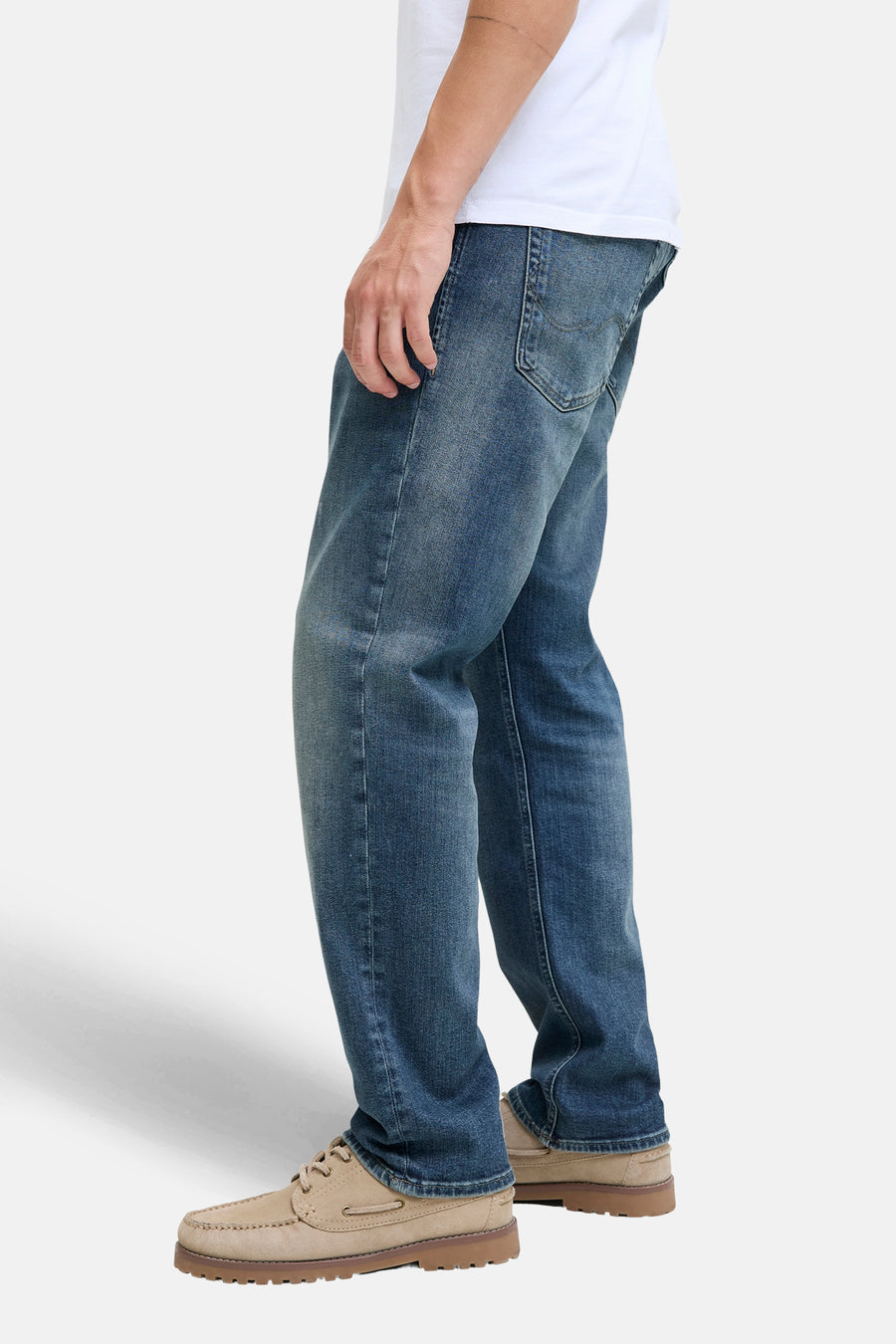 Rechte jeans van middinblauw denim van JACK & JONES JEANS INTELLIGENCE gedragen met een wit T-shirt en suède bootschoenen.