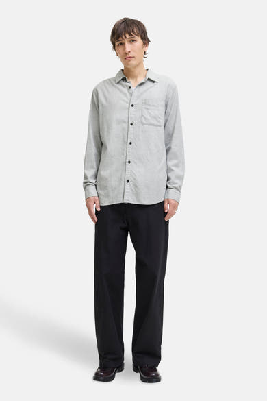 Grijs overhemd met lange mouwen van ORIGINALS BY JACK & JONES, gedragen met een wijde zwarte broek en leren schoenen.