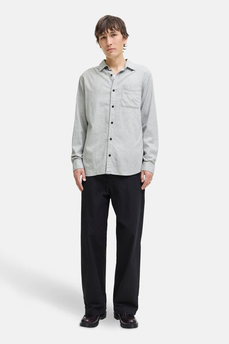 Grijs overhemd met lange mouwen van ORIGINALS BY JACK & JONES, gedragen met een wijde zwarte broek en leren schoenen.