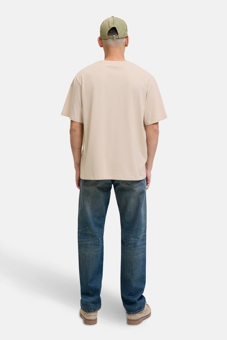 T-shirt à manches courtes écru de ORIGINALS BY JACK & JONES, porté avec un jean bleu et une casquette kaki.