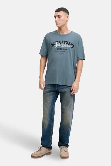 Blauw T-shirt met korte mouwen van ORIGINALS BY JACK & JONES, met een print op de voorkant, gedragen met een spijkerbroek en beige schoenen.