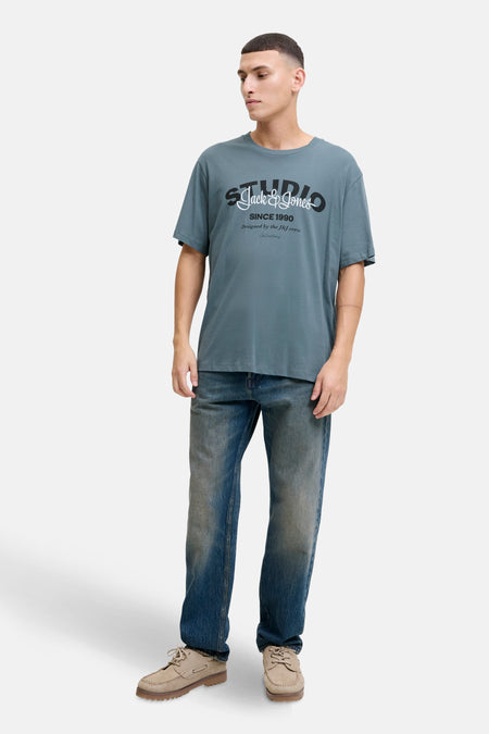 Blauw T-shirt met korte mouwen van ORIGINALS BY JACK & JONES, met een print op de voorkant, gedragen met een spijkerbroek en beige schoenen.