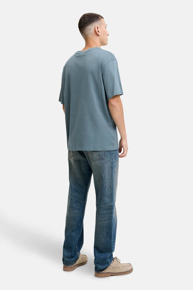 Blauw T-shirt met korte mouwen van ORIGINALS BY JACK & JONES, gedragen met een blauwe jeans en beige bootschoenen.