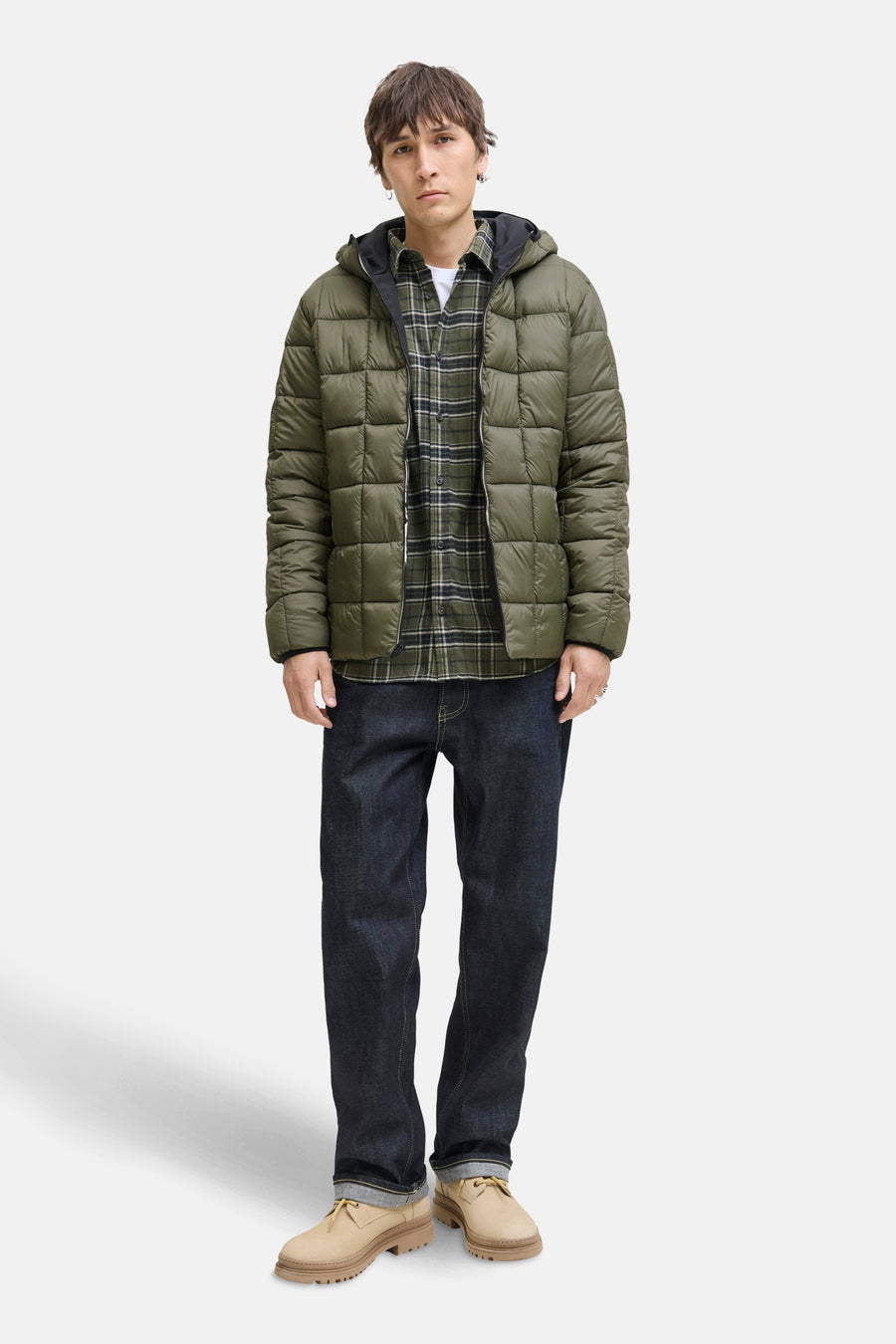 Zwarte regenjas van JACK & JONES met een gewatteerd pufferjack-ontwerp, gedragen over een geruit overhemd en een donkere spijkerbroek.
