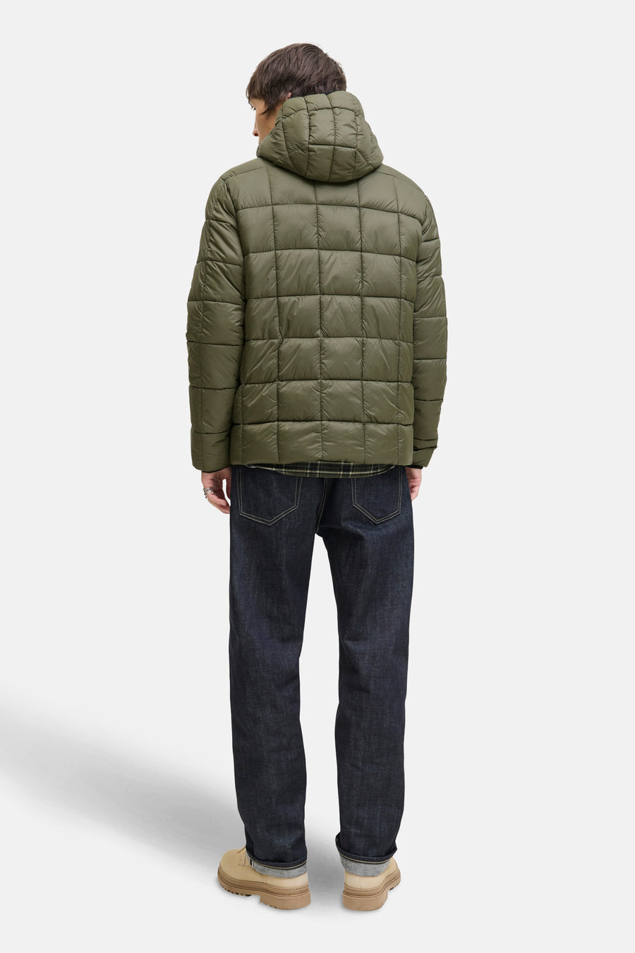 Groene gewatteerde regenjas van JACK & JONES, gedragen met een donkerblauwe jeans en beige schoenen.