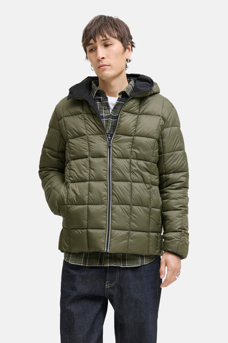 Zwarte regenjas van JACK & JONES met capuchon, gedragen over een geruit overhemd en een spijkerbroek.
