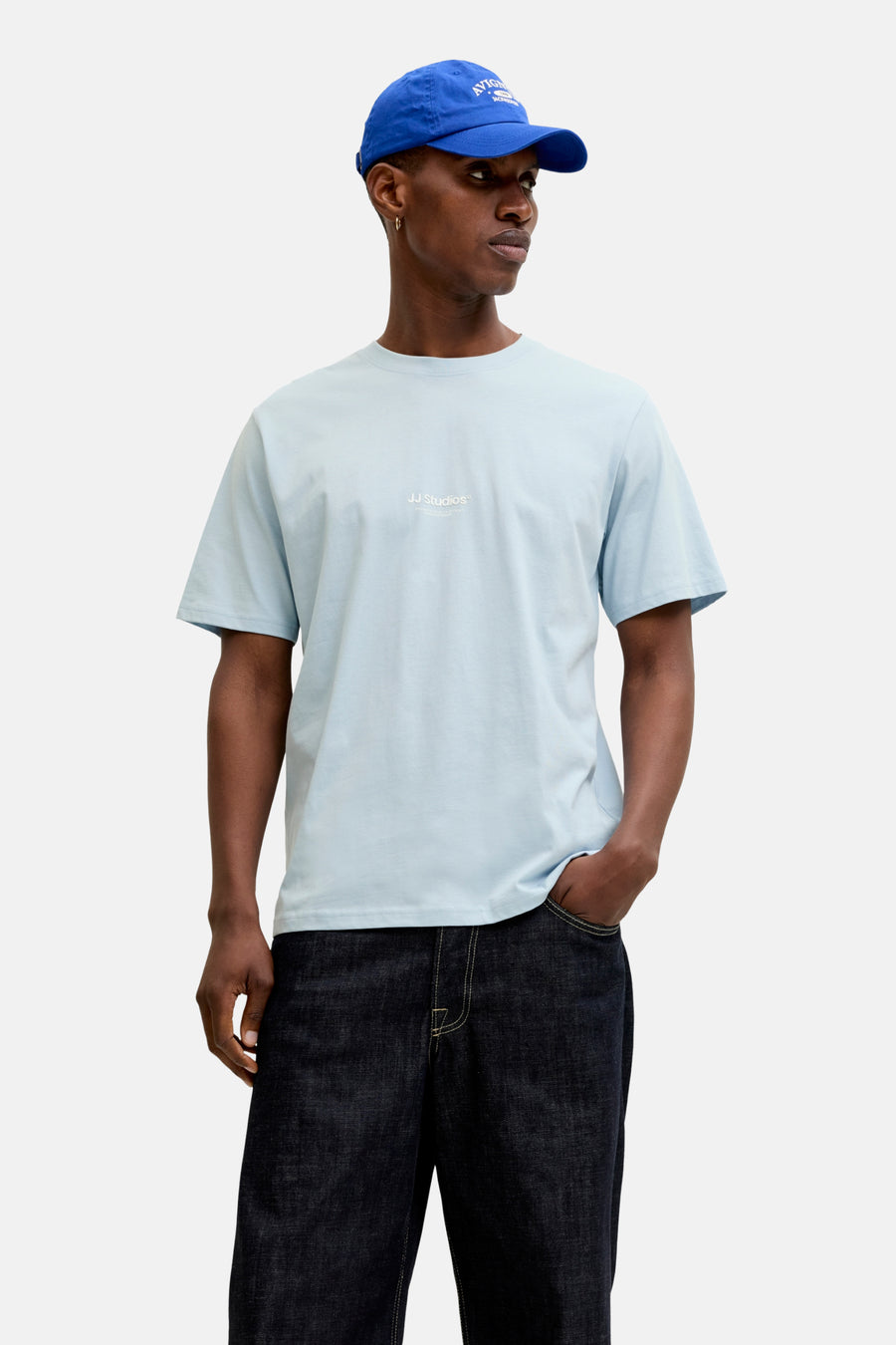 T-shirt à manches courtes bleu de JACK & JONES, porté avec un jean foncé et une casquette bleue.
