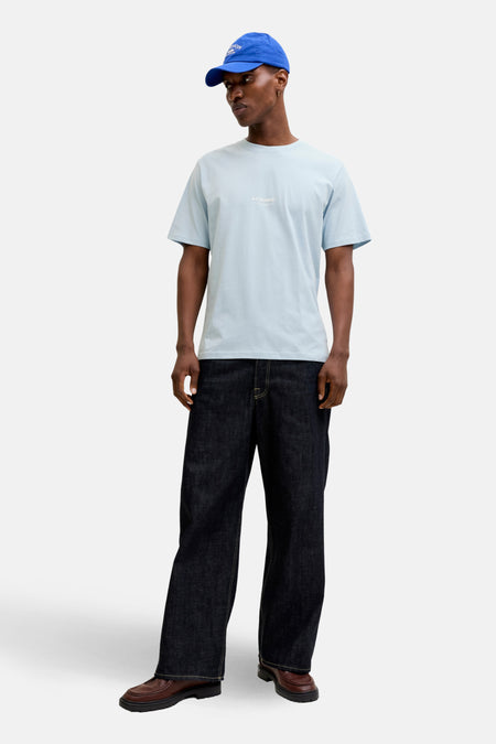 T-shirt à manches courtes bleu de JACK & JONES, porté avec un jean large et des mocassins marron.