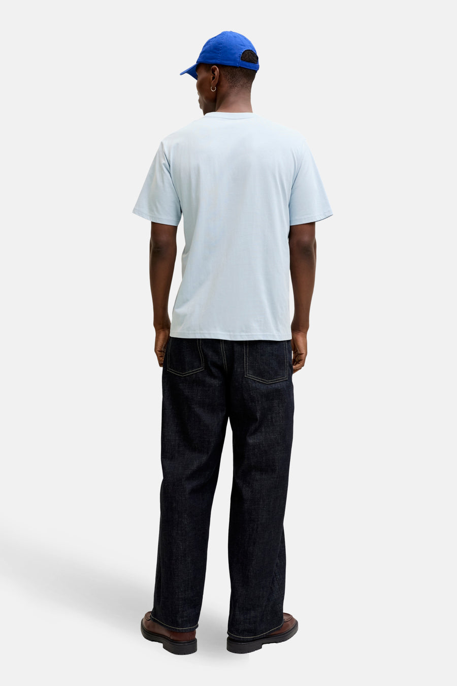 T-shirt bleu à manches courtes de JACK & JONES, porté avec un pantalon denim ample et des chaussures marron.
